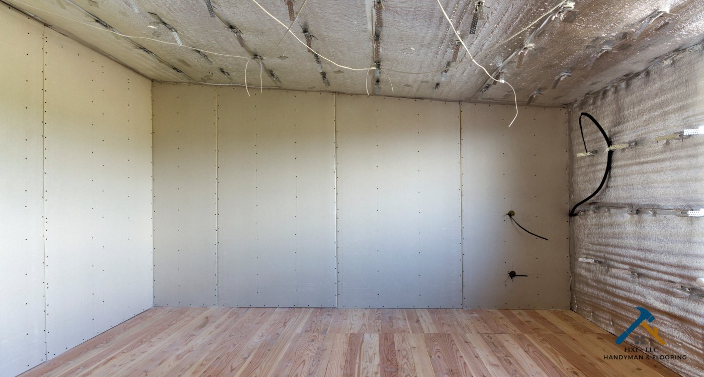 Drywall Services by FIXI LLC in Utah County A room with newly installed drywall panels and exposed ceiling insulation, showcasing professional drywall services in Utah County by FIXI LLC...