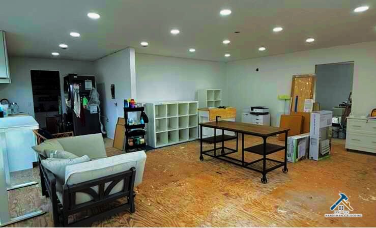 FIXI LLC Remodeling and Flooring Services Company Utah County Open-concept living space under renovation in Utah County, featuring exposed subflooring, bright white walls, and modern recessed lighting. The room showcases shelving units, minimal furniture, and remodeling materials, highlighting home improvement and flooring services by FIXI LLC, a woman-owned remodeling company in Provo, Utah...